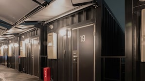 A row of dark-colored, numbered hotel rooms with individual lighting and a red fire extinguisher. - Hotel R9 The Yard Ashikagaekinishi (Ashikaga)