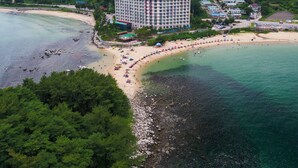 Hotel à beira-mar com um edifício grande, praia e montanhas ao fundo.