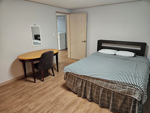 Un dormitorio con cama, escritorio y silla.