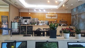 Um café moderno com balcão, área de estar e grandes janelas.