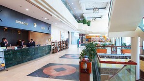 Um saguão de hotel com balcão de recepção, ponto de informações e escadaria.