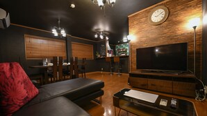 Un soggiorno moderno con un divano, un tavolino, una TV e una parete in legno con un orologio.