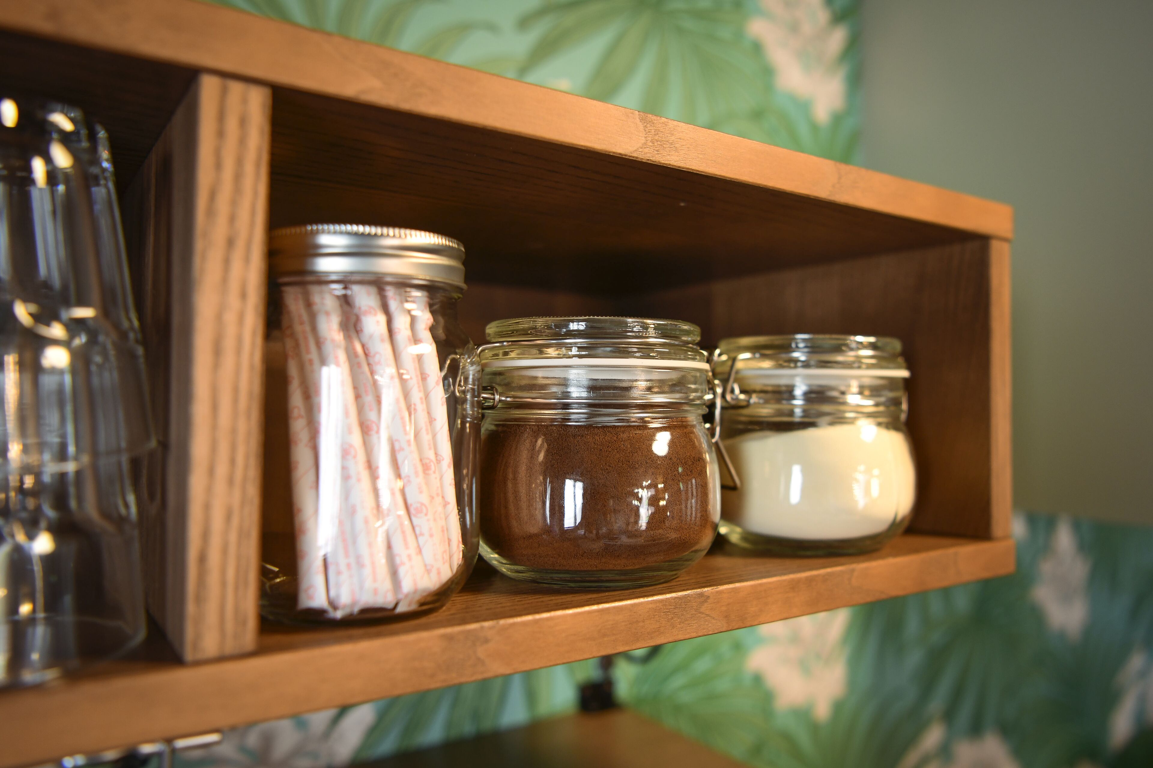 A wooden shelf with three glass jars containing different substances.