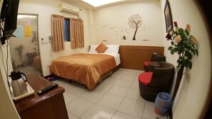 A hotel room with a bed, a desk with a coffee maker, a chair, a small table, and a wall-mounted TV. - Wen Shan (Yuchi)