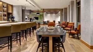 A modern hotel lobby with a bar area, seating, and a large window. - Hyatt Place Prince George (Prince George)