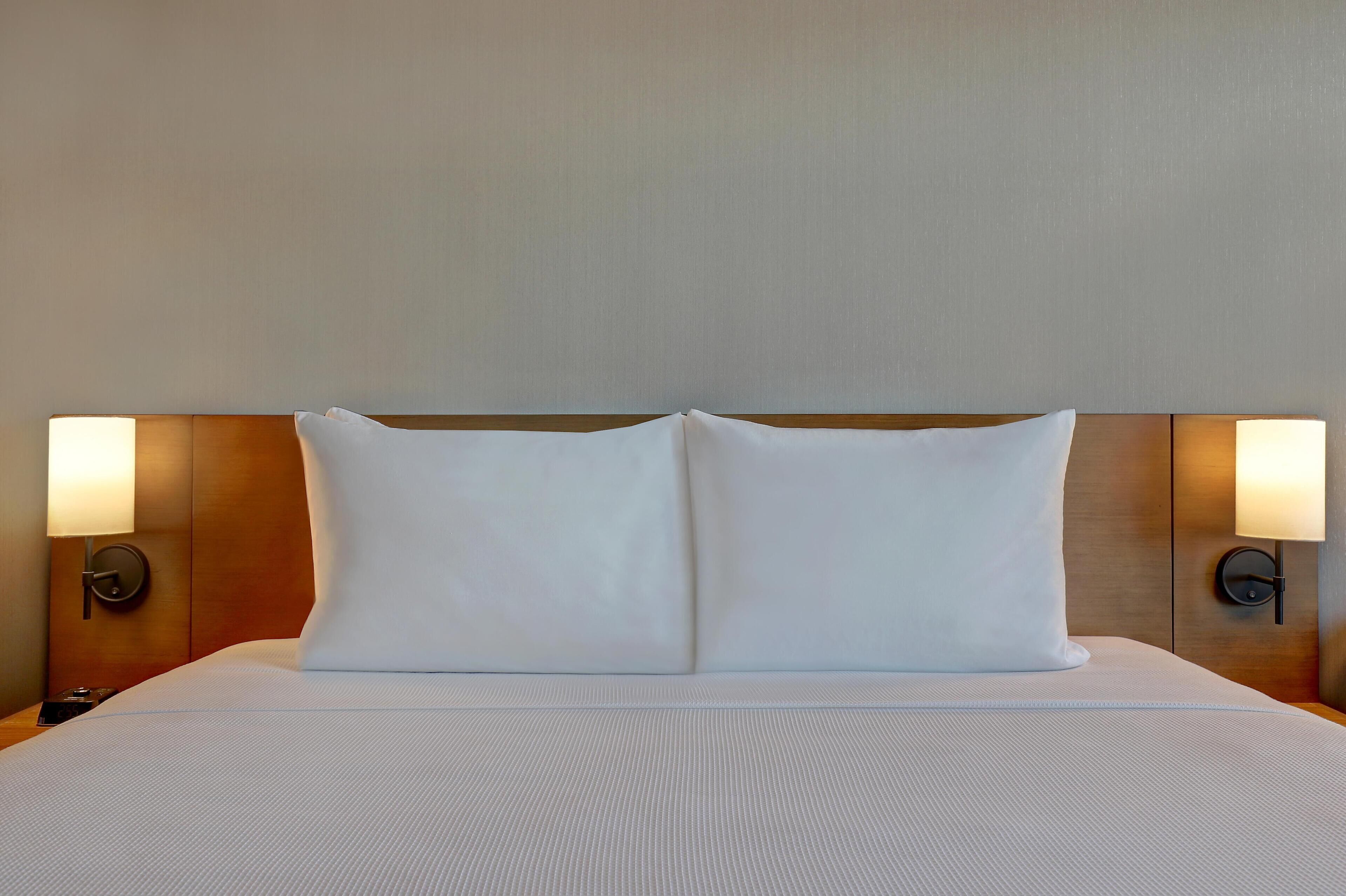 A hotel room with a large bed, two bedside lamps, and a wooden headboard.
