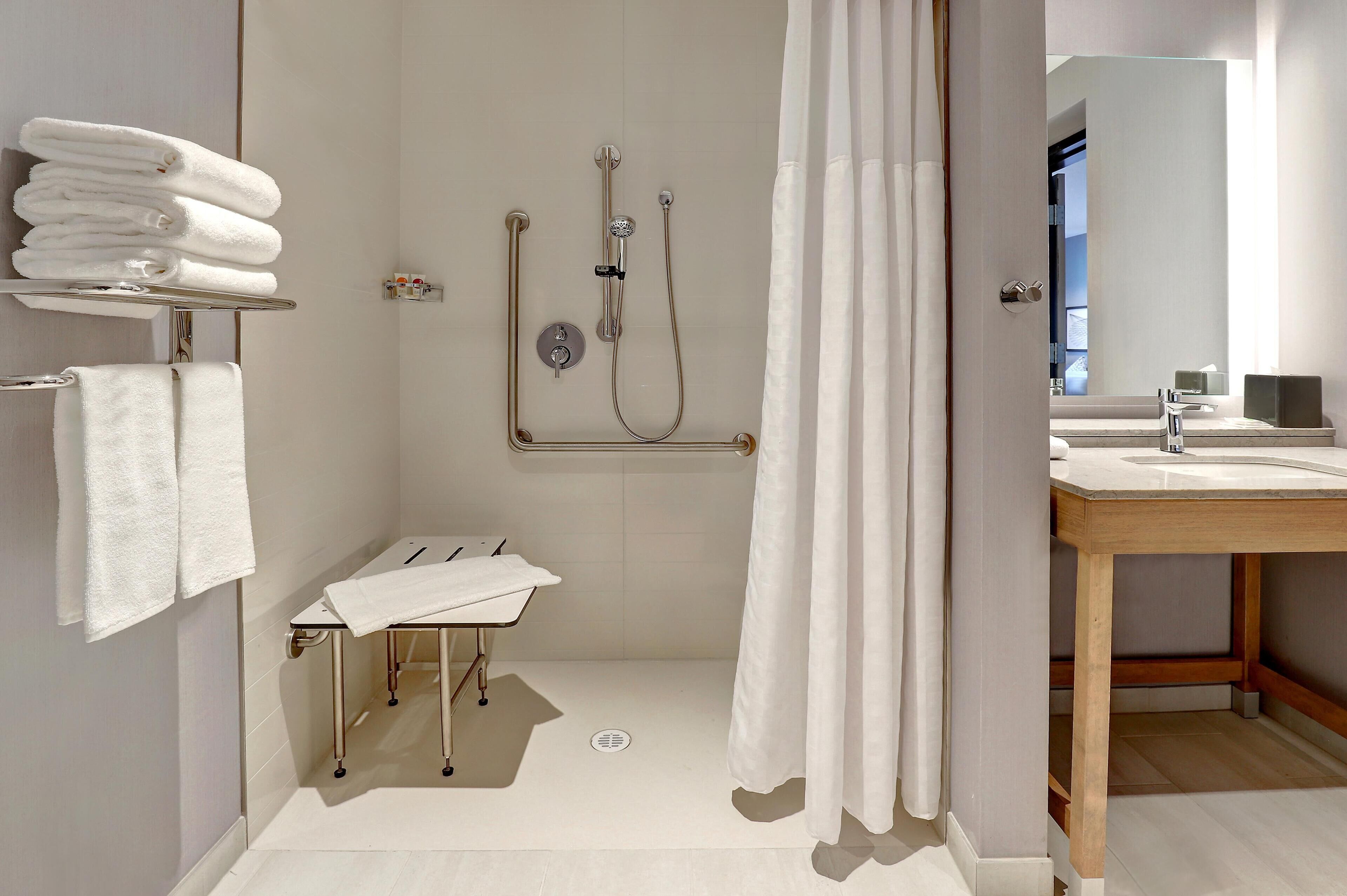 A modern bathroom with a shower, a sink, and a mirror.