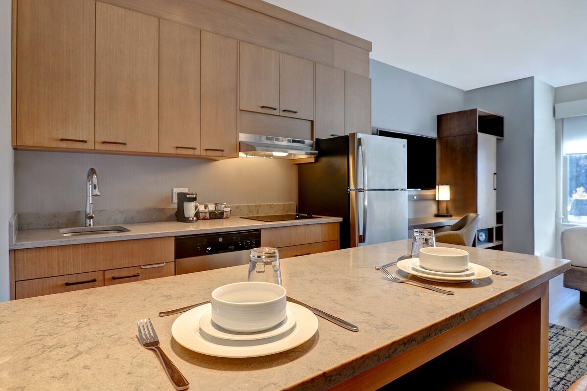 A modern kitchen with wooden cabinets, stainless steel appliances, and a marble countertop.