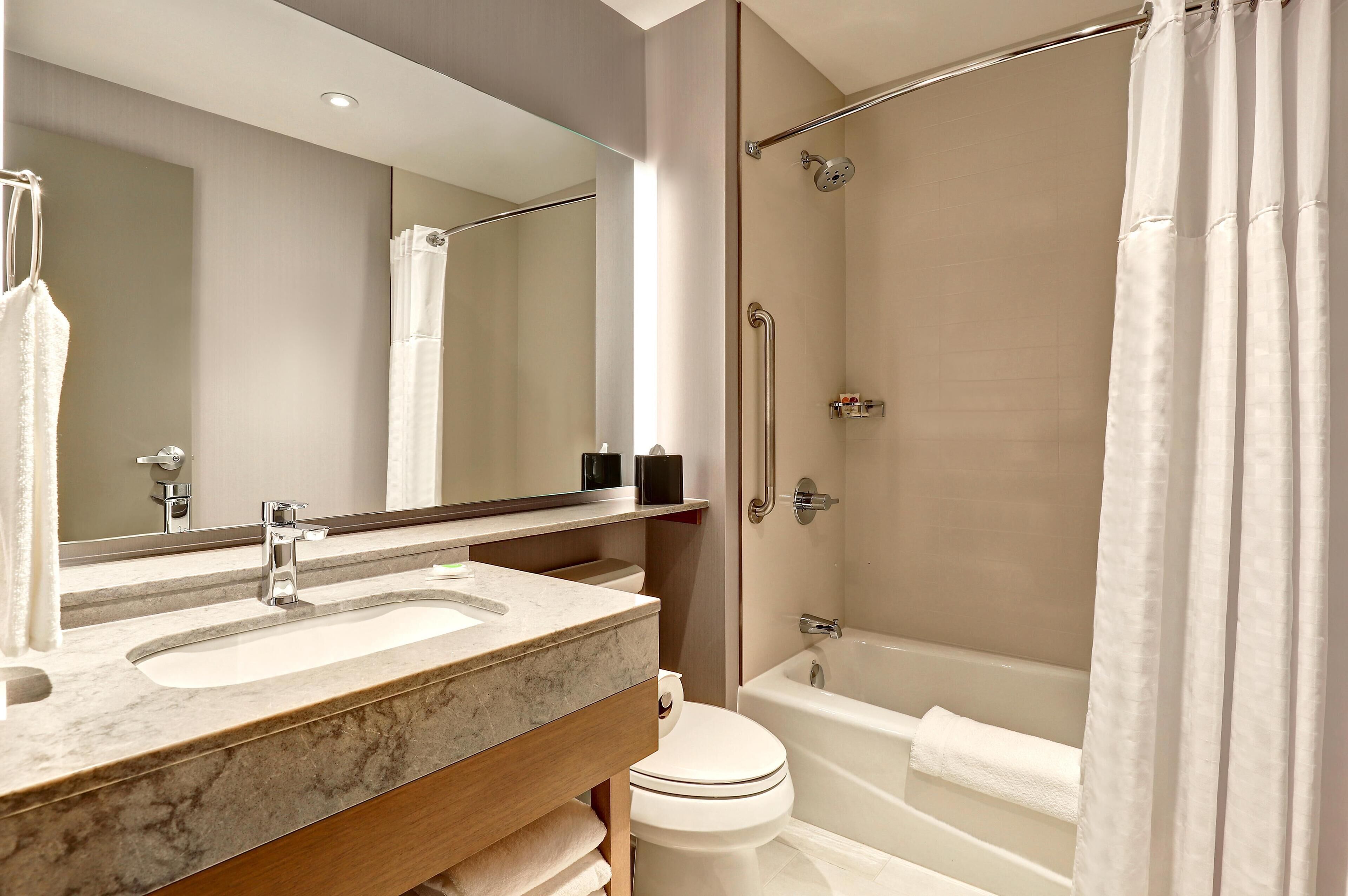 Un baño moderno con tocador doble lavamanos, inodoro, bañera y cabina de ducha.