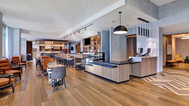 A modern hotel lobby with a bar area, seating arrangements, and a reception desk. - Hyatt Place Prince George (Prince George)