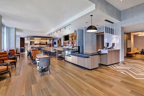 A modern hotel lobby with a bar area, seating arrangements, and a reception desk. - Hyatt Place Prince George (Prince George)