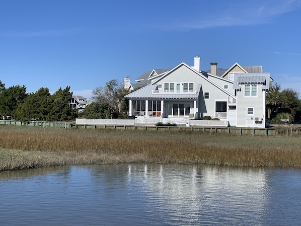 A two-story house with a large porch, a covered deck, and a view of a body of water.