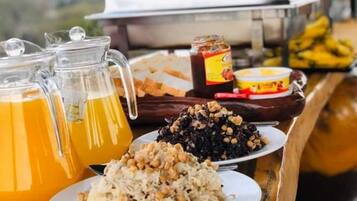Una mesa con una jarra de jugo de naranja, un plato de comida y un frasco de mermelada.