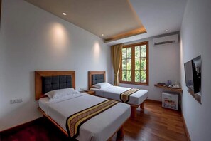 Quarto de hotel com duas camas, televisão, mini-frigorífico e janela com cortinas.