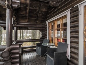 A wooden log cabin with a wooden deck, a table, and four chairs. - Tavintupa by Interhome (Pertunmaa)