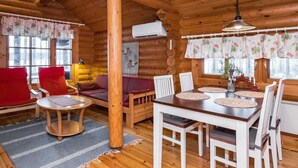 A cozy log cabin interior with a dining table, chairs, a sofa, and a fireplace. - Tavintupa by Interhome (Pertunmaa)