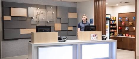 Una moderna recepción con mostrador, pantalla digital, caja registradora y área de atención al cliente.