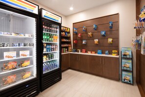 Exposição refrigerada com diversos alimentos e um expositor de lanches na parede.