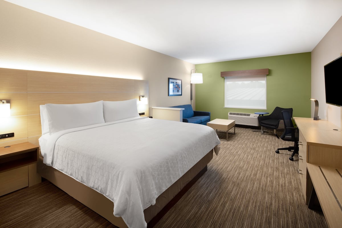 Een hotelkamer met een groot bed, een bureau, een stoel en een televisie.