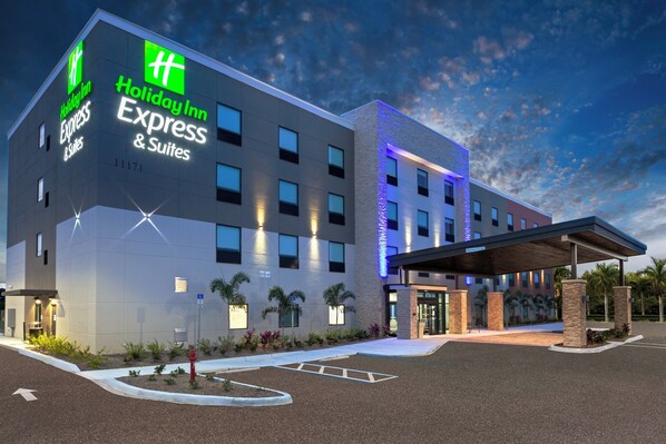 Un bâtiment de la chaîne Holiday Inn Express & Suites, doté d’une façade moderne, de nombreuses fenêtres et d’un espace d’entrée abrité.