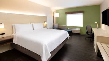 Habitación de hotel con una cama grande, un escritorio con silla, un televisor de pantalla plana y una ventana con persianas.