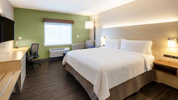 Habitación de hotel con cama, escritorio, silla y televisor.