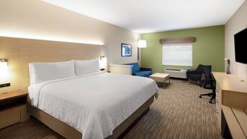 A hotel room with a large bed, a desk, a chair, and a TV.