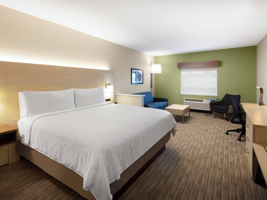Una habitación de hotel con una cama grande, un escritorio, una silla y un televisor.