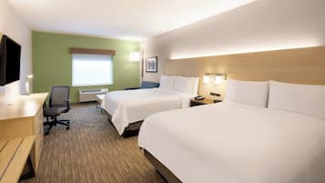 Ett hotellrum med två sängar, ett skrivbord, en stol, en tv och ett fönster.