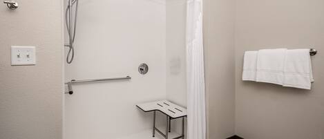 Un baño moderno con ducha, un pequeño banco y un perchero para toallas.