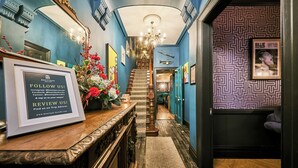 A hallway with a wooden staircase, a framed sign, and a patterned wall.