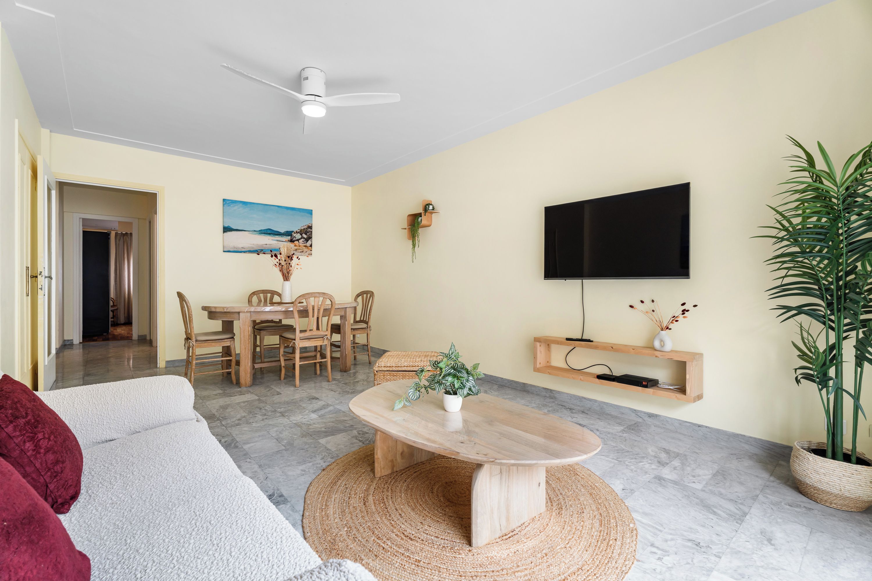Sala de estar com sofá, mesa de centro, TV e área de jantar com cadeiras e mesa.