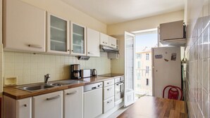 Een keuken met witte kastjes, een houten aanrecht, een spoelbak, een koffiezetapparaat en een koelkast.