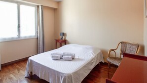 Een slaapkamer met een bed, een stoel, een tafel en een lamp.