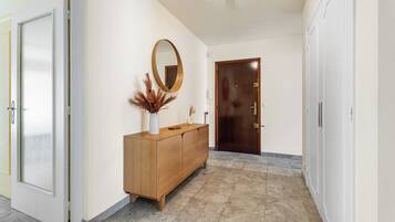 Un couloir avec une armoire en bois, un miroir et une porte.