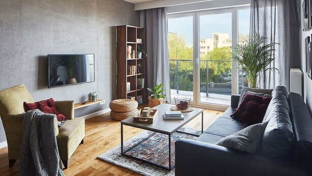 A modern living room with a sofa, armchair, coffee table, and bookshelf. - Elegant Apartment in Zoliborz | Balcony and Parking (Warszawa)