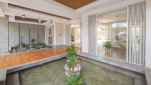 A spacious lobby with a wooden reception desk, a central planter with plants, and a modern ceiling design. - Kiluwa Apartments & Spa  by Dunhill Serviced Apartments (Nairobi)