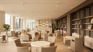 Un espace de détente moderne, avec des meubles en osier, une table basse centrale et une bibliothèque remplie de livres.