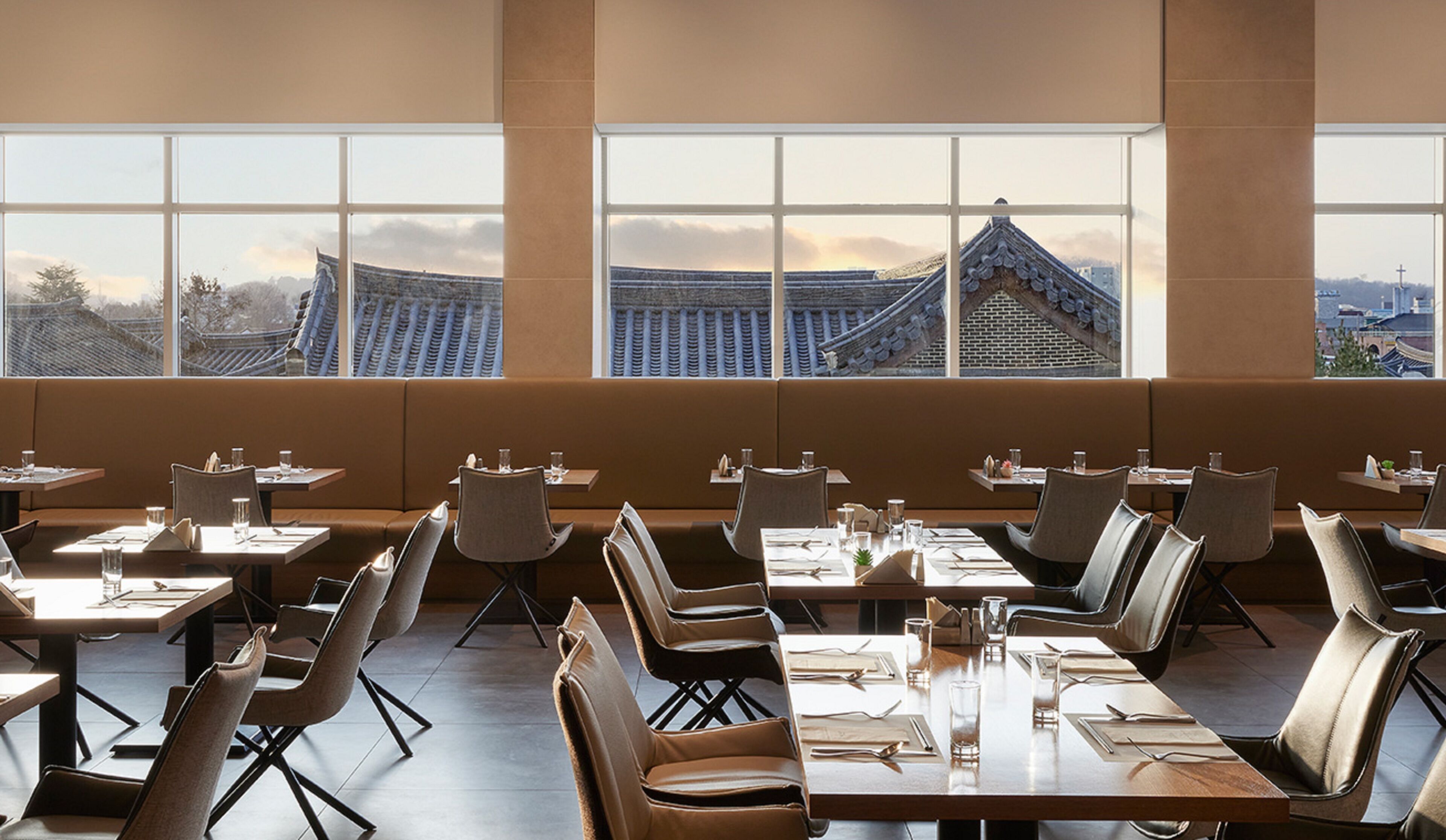 A restaurant with tables and chairs arranged for dining, large windows offering a view of traditional architecture.
