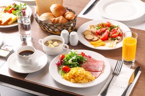 A breakfast setting with plates of eggs, ham, and salad, a basket of croissants, and a glass of orange juice. - Lahan Hotel Jeonju (Jeonju)