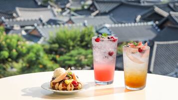 A table with a dessert and two drinks, set against a backdrop of traditional architecture.