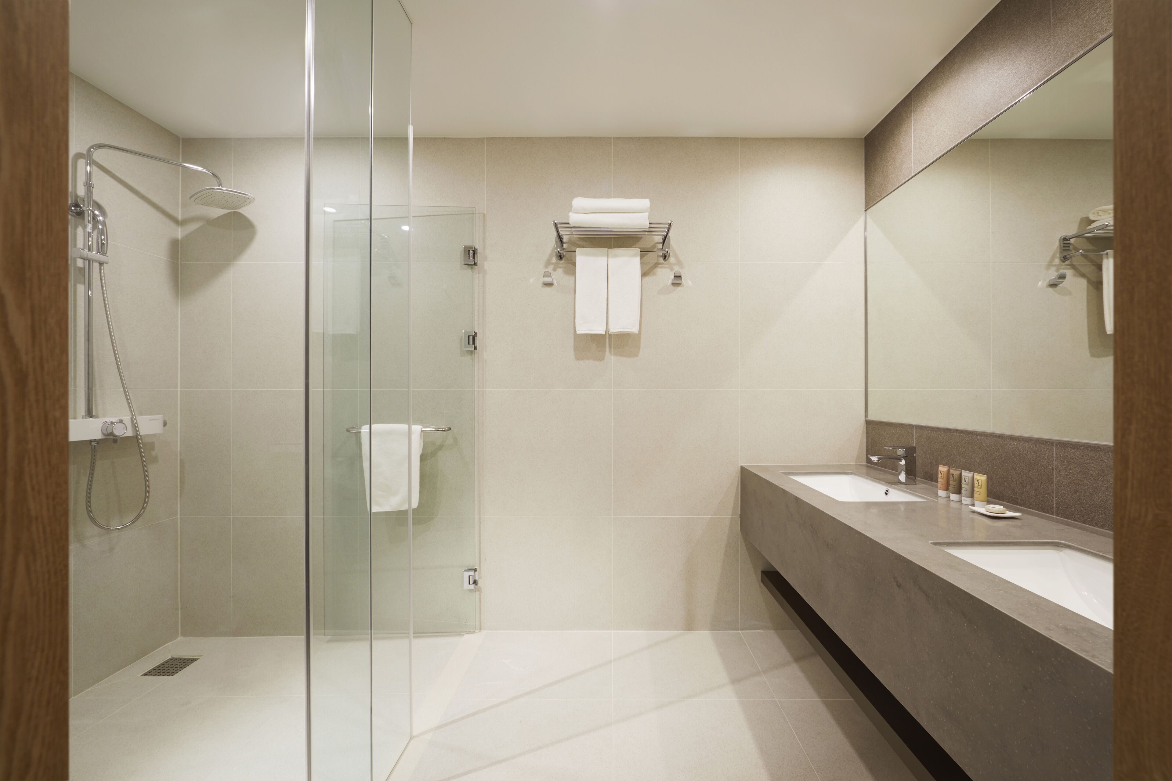 A modern bathroom with a glass shower enclosure, two sinks, and a large mirror.