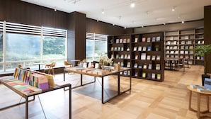 Een modern bibliotheekinterieur met houten vloeren, grote ramen en boekenplanken.