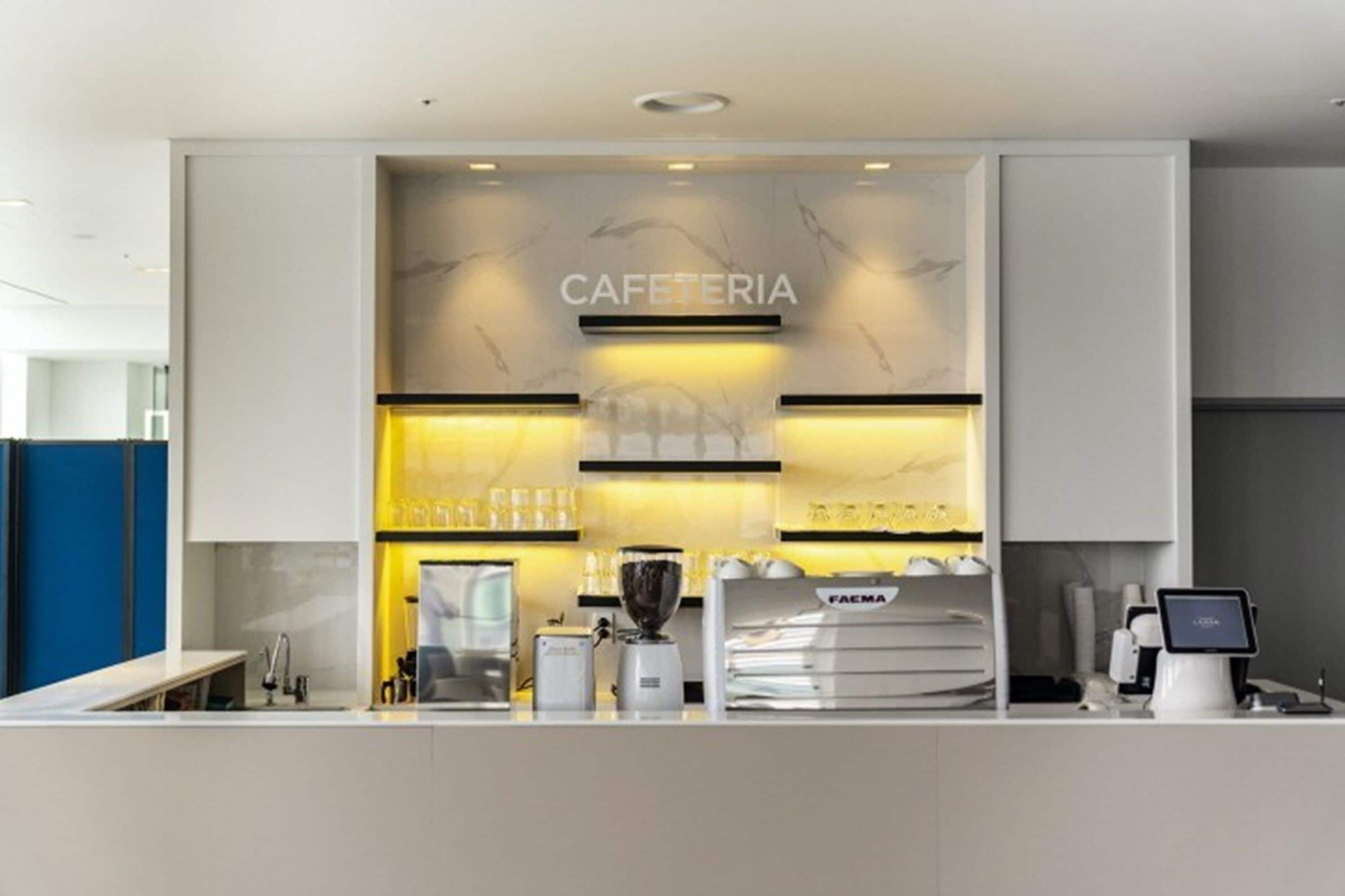 A modern cafe with a marble wall, a coffee machine, and a digital payment terminal.