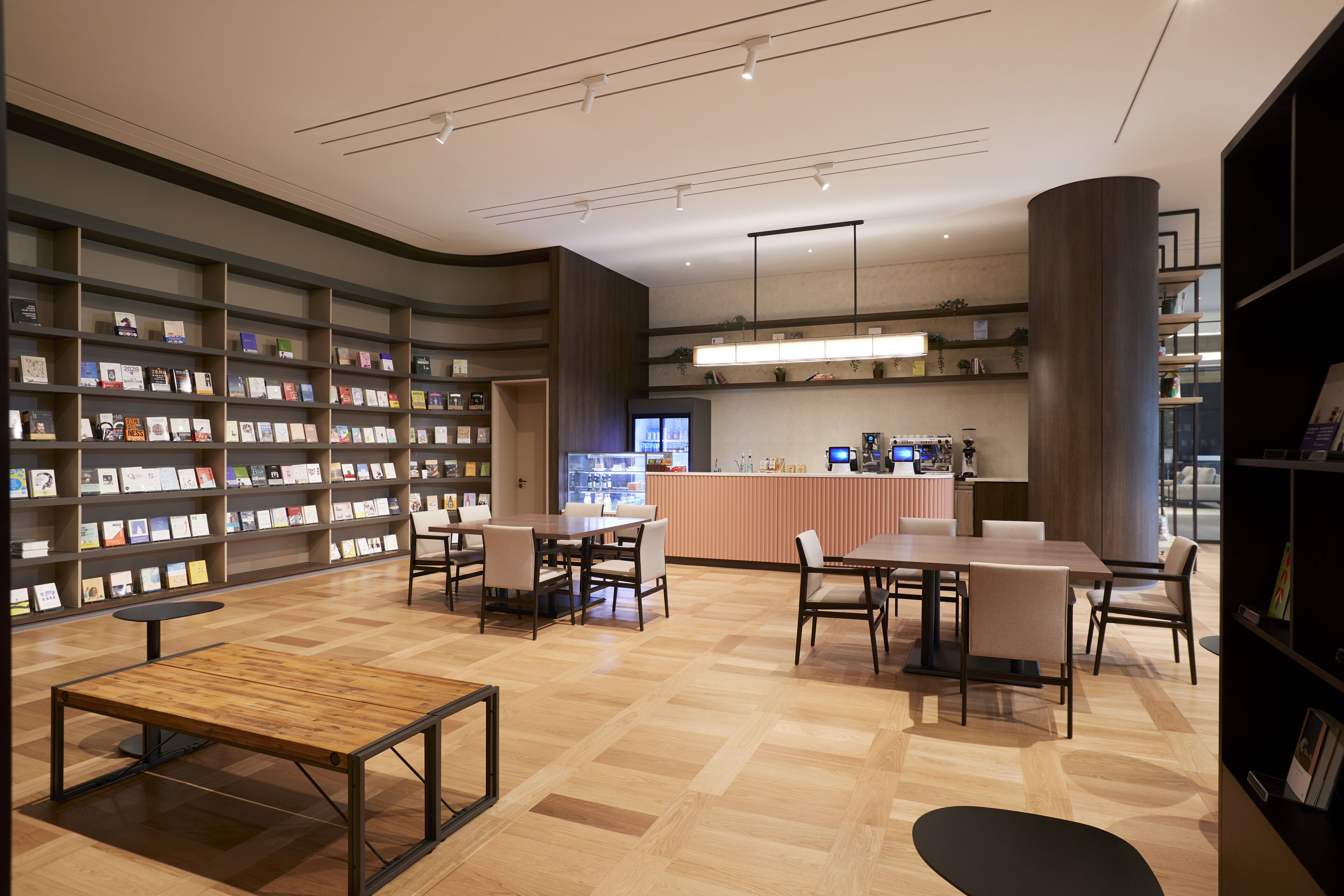 A modern library with bookshelves, tables, and a reception area.