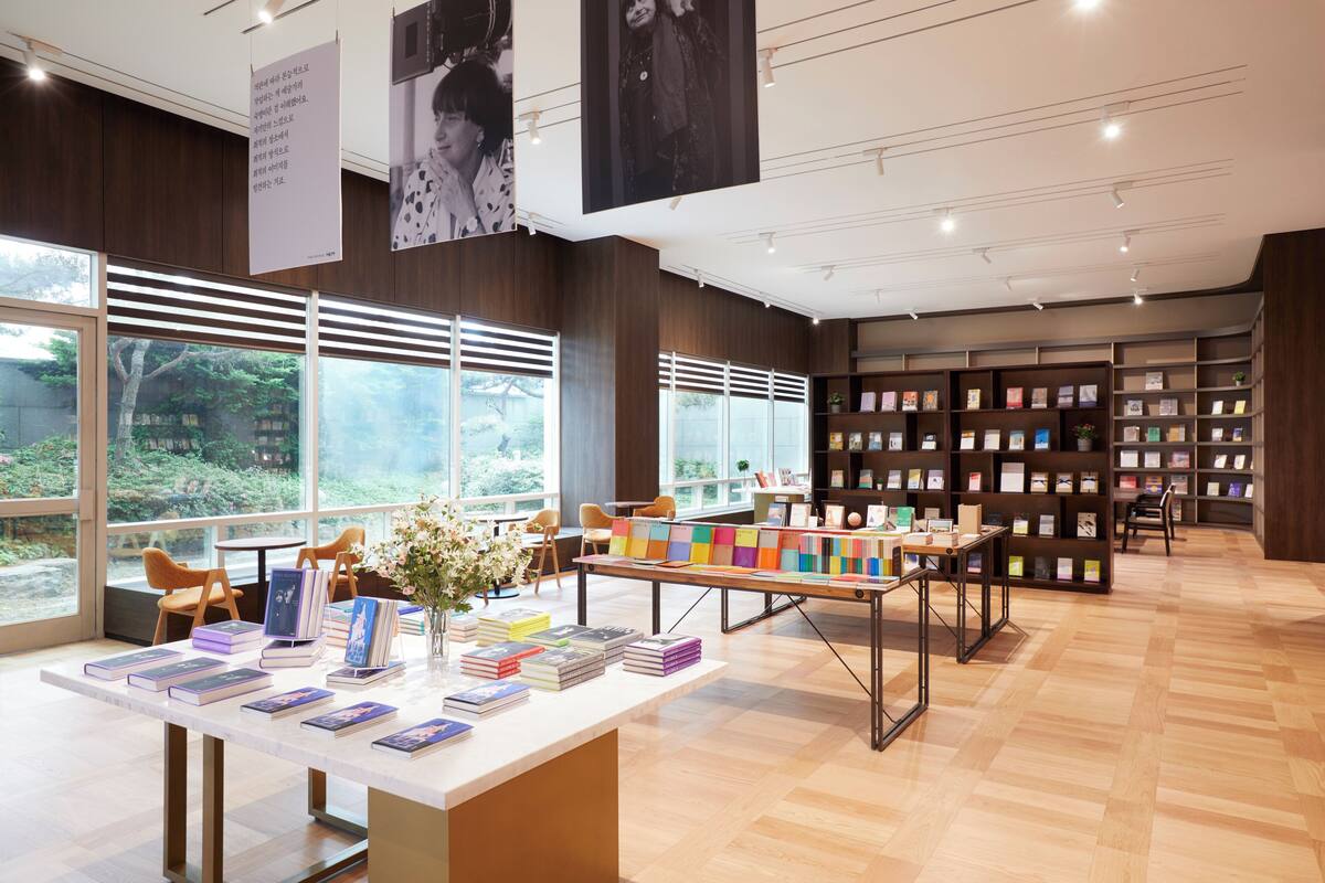 Une librairie avec des étagères, des tables, des chaises et de grandes fenêtres.