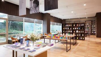 Uma livraria com estantes, mesas, cadeiras e janelas amplas.