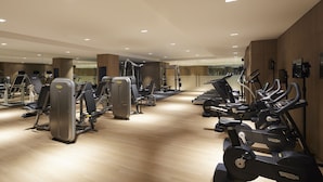 Een sportschool met diverse fitnessapparaten, waaronder loopbanden en krachttrainingsmachines, gerangschikt in rijen.