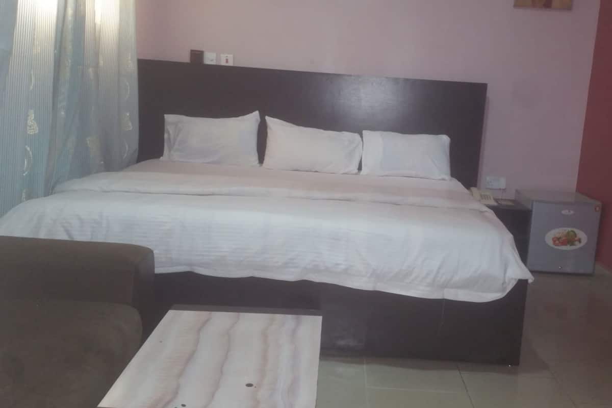 Ein Hotelzimmer mit Bett, Nachttisch, kleinem Tisch und einer Wandverkleidung.