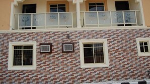 A two-story building with a patterned facade, a balcony with frosted glass railings, and multiple windows.